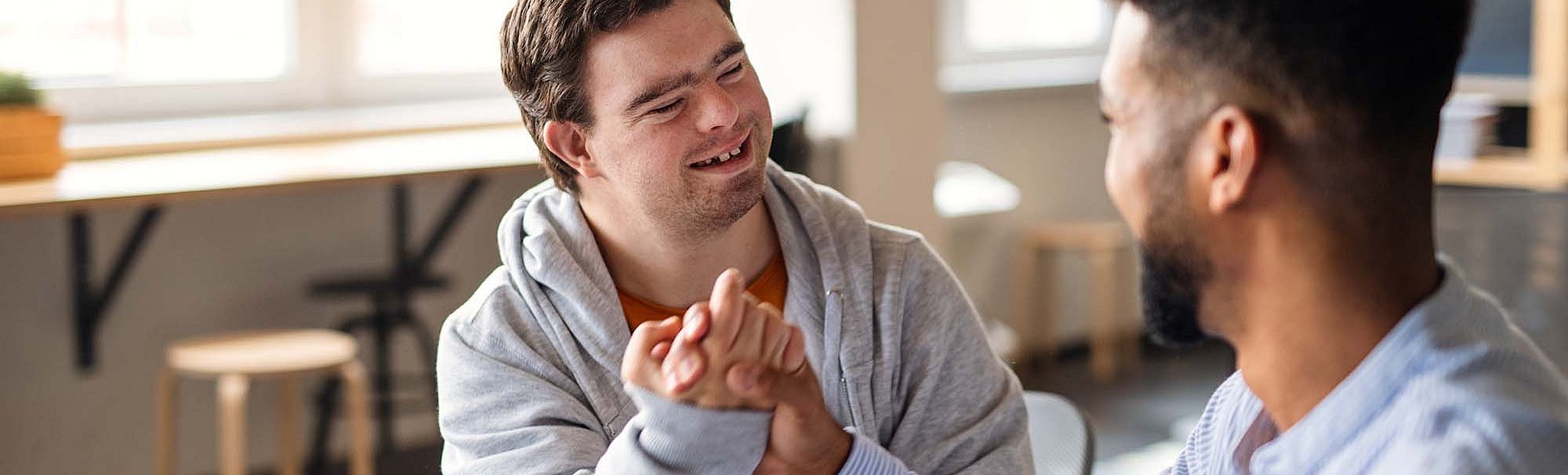 Zwei Männer, einer davon mit Down Syndrom, machen einen Bro-Handshake